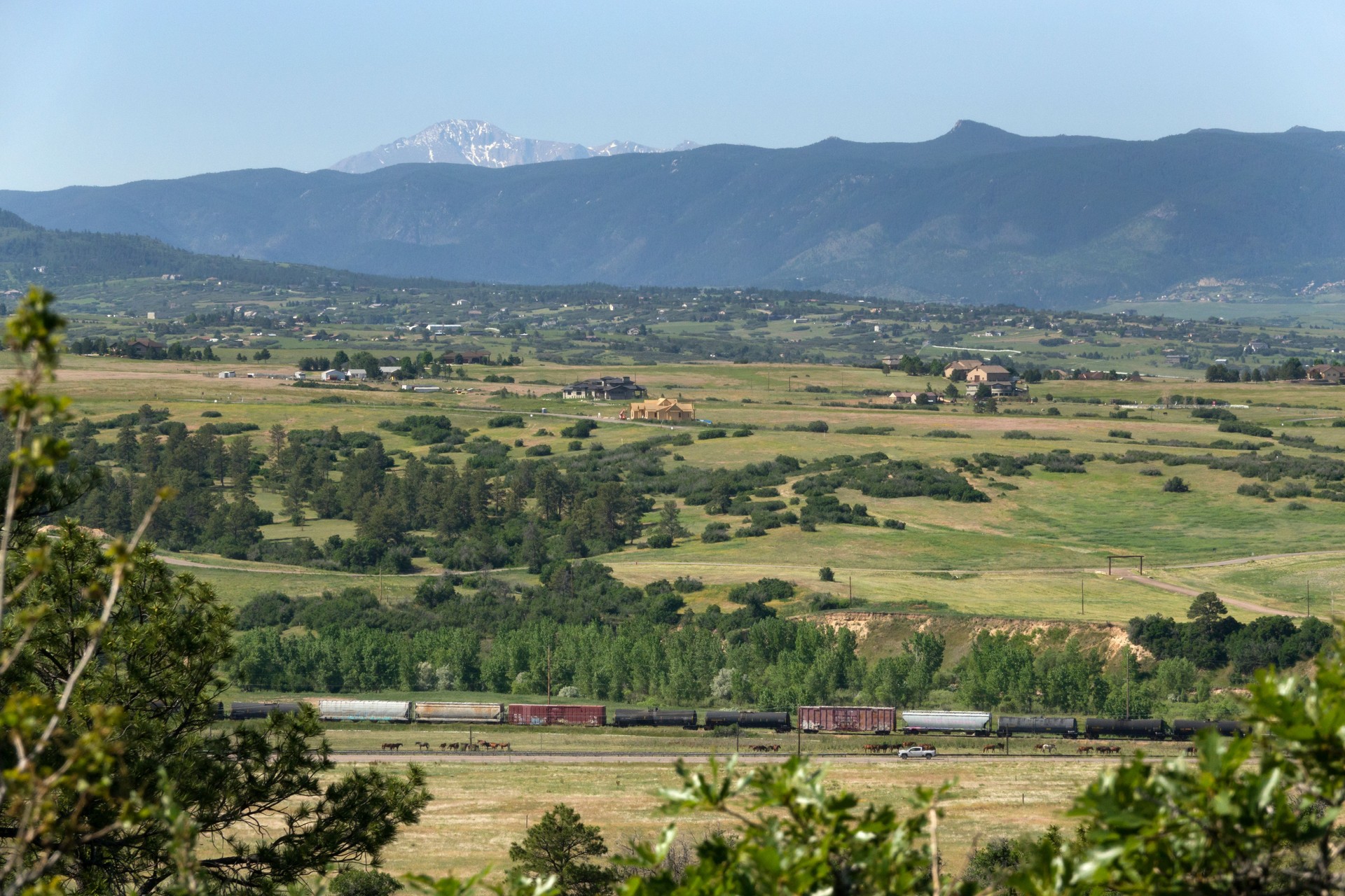 Train rolls past distant Pikes Peak Sedalia homes Colorado
